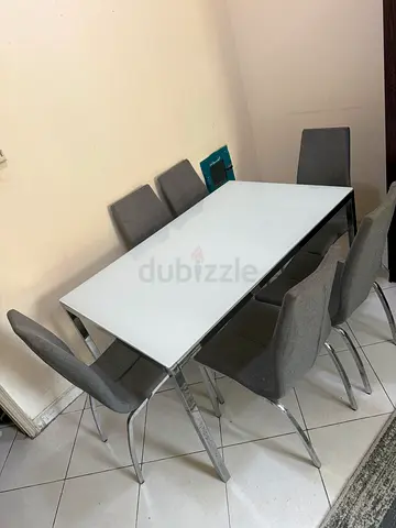Modern white glass dining table with 6 grey upholstered chairs