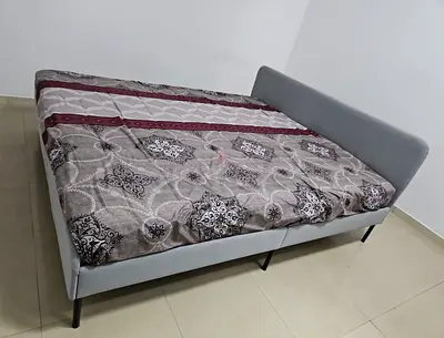 Light grey fabric double bed with low headboard and metal legs