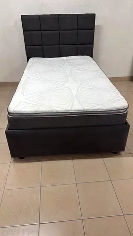 A modern single bed featuring a padded headboard