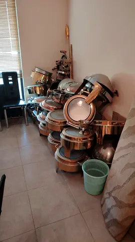 stainless steel food chafing dishes/buffet warmers stacked together indoors