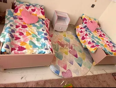 Pair of pink toddler beds with bedside table  heart-themed bedding. Memory form mattresses included