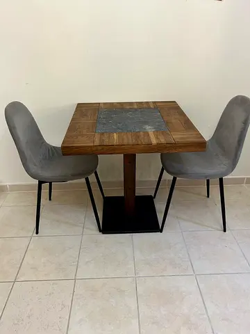 Small wooden dining table with two grey upholstered chairs