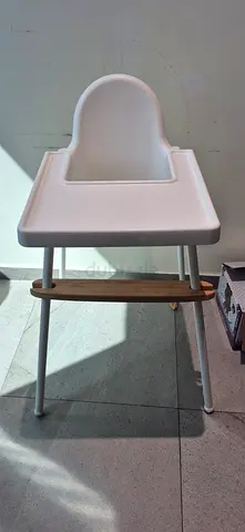 Simple white baby high chair with tray and wooden footrest - 25 dhs