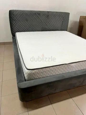 This bed is upholstered in grey velvet paint and features a geometrically designed, padded headboard