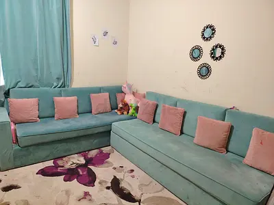 L-shaped teal velvet sofa set with pink cushions - good condition