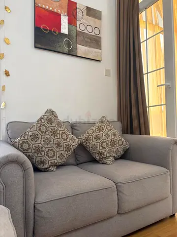 Two-seater light grey fabric sofa in good condition and new barely used From home center