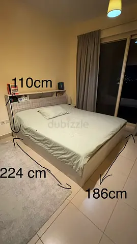 King size bed with headboard shelf and mattress side bed tables and a vanity table with mirror.