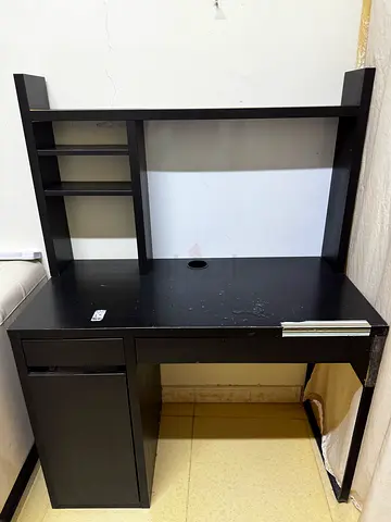 Compact black computer desk with shelving and drawer