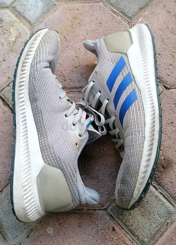 Adidas-style sneakers with blue stripes, used