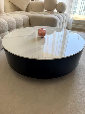 Round low-profile coffee table with glass top and black base
