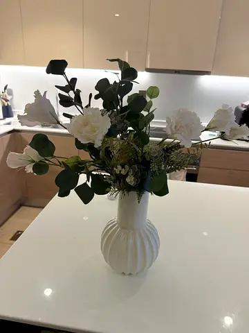 White ceramic vase with artificial roses and eucalyptus arrangement