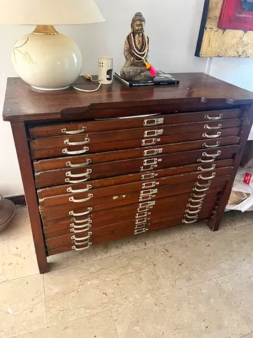 This is an antique wooden plan chest featuring multiple flat file drawers with silver-colored metal