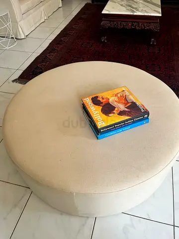 This is a modern round ottoman in a cream fabric