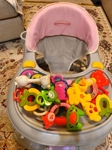 Used baby walker with activity tray and assorted toys (pink/grey) and potty.