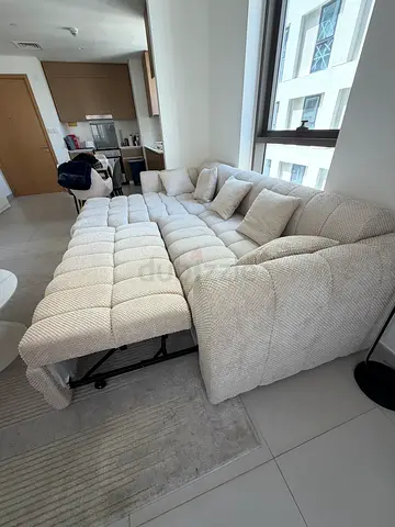 Compact L-shaped beige fabric sofa with pull-out bed (good condition)