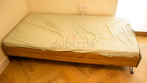 Single wooden bed frame with mattress - simple mid-century style.