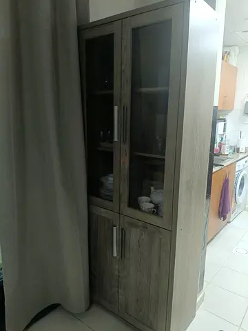 Tall wooden display cabinet with glass doors — good condition