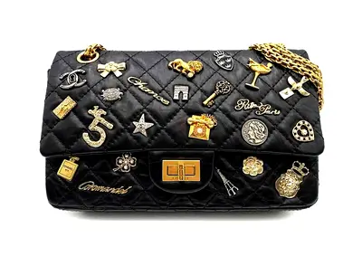 Elegant black quilted flap bag with gold-tone details and unique decorative charms. Pre-owned