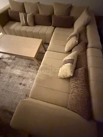 Large L-shaped beige fabric sectional sofa with cushions