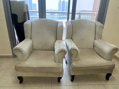 Pair of beige upholstered wingback armchairs — sturdy wooden legs