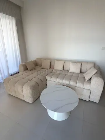 Beige L-shaped sectional sofa in good condition with cushions