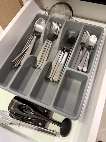 Cutlery tray with assorted stainless steel utensils dishes and kitchen tools