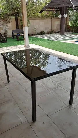 Outdoor rattan-style dining table with glass top - good condition