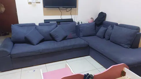 L-shaped blue fabric sofa with cushions - good condition