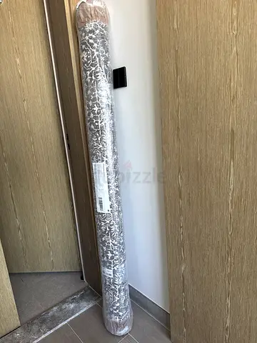 New rolled area rug — neutral gray/white pattern, still wrapped