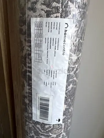 New rolled area rug — neutral gray/white pattern, still wrapped
