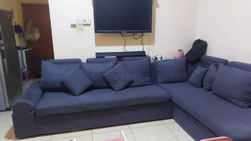 L-shaped blue fabric sofa with cushions - good condition