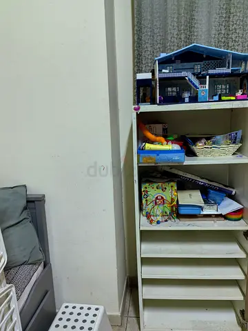 Small white wooden toy shelving unit with dolls house and toys