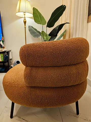 Rust color boucle accent chair with curved back and black legs