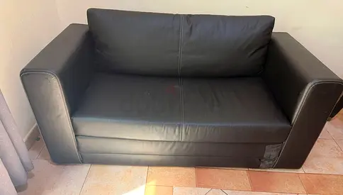 Two-seater black leather sofa in good used condition