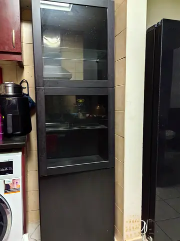 Tall dark wood glass-front cabinet — sturdy kitchen/storage unit