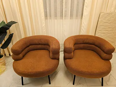 Rust color boucle accent chair with curved back and black legs