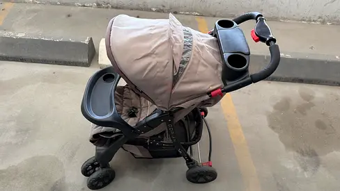 Moderately used beige baby stroller with parent and child trays