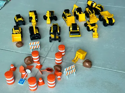 Set of small yellow construction toy vehicles with traffic cones and accessories