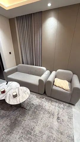 Light grey modern 3-seater sofa with matching armchair and rug