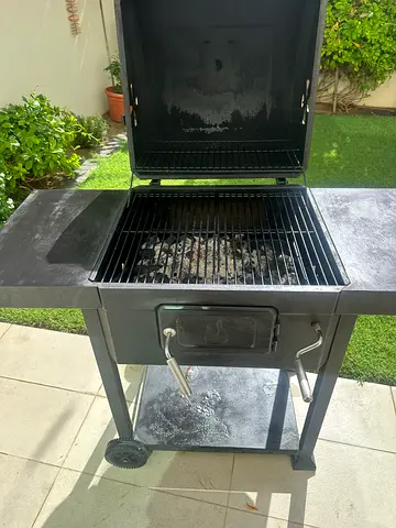 Used charcoal BBQ grill with side shelves and wheels