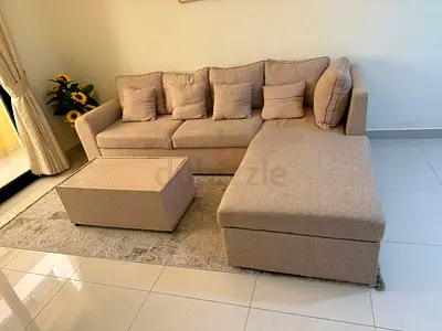 Beige L-shaped Sofa with Ottoman and Cushions - Good Condition