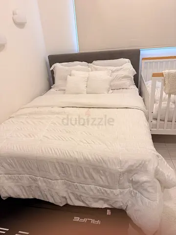 Queen bed with white bedding set and padded headboard (used)