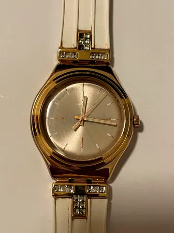 Swatch Gold-tone womens wristwatch with white band and crystal accents