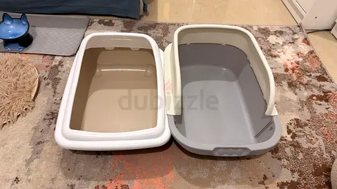 Two clean cat litter trays - one white/tan and one grey (used)