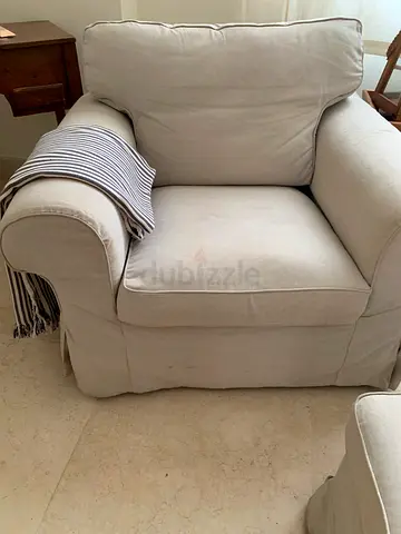 Beige Upholstered Armchair with Cushioned Seat and Pillow