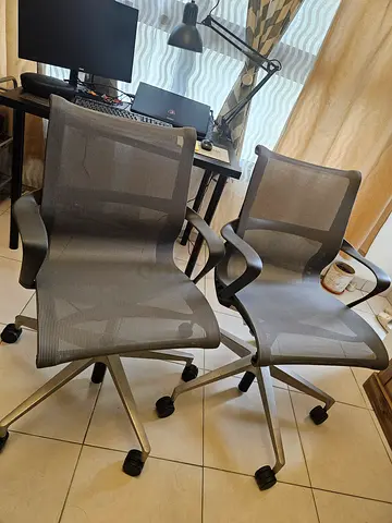 Pair of ergonomic grey mesh office chairs on wheels