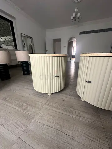 Pair of cream ribbed round bedside tables with marble tops and painted solid wood