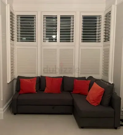 Compact L-shaped grey sofa bed with cushions - good condition