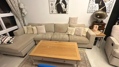 Light beige L-shaped sectional sofa with wooden coffee table and frames