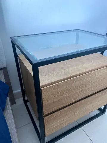 Modern glass-top side table with wooden drawers and black metal frame